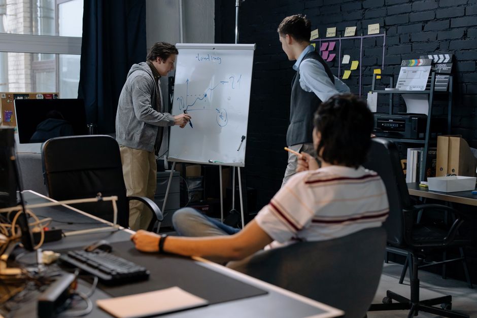Economia São Paulo — Business team in a modern office brainstorming ideas on a whiteboard. Engaged discussion and planning.